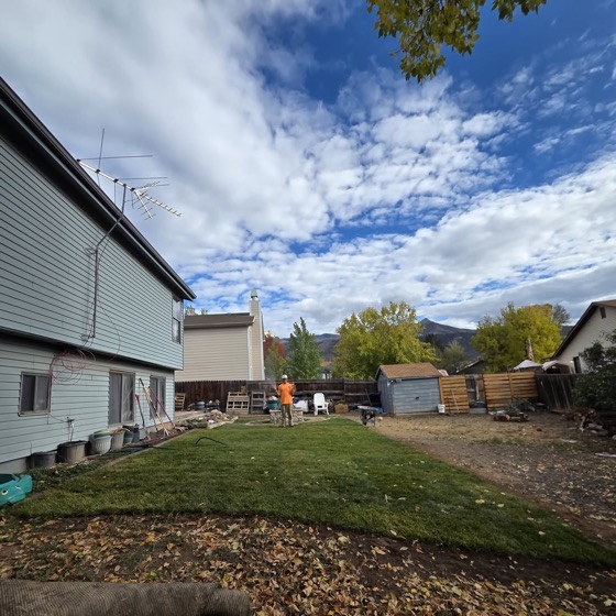 Bright green fresh turf in a backyard with mountains and a dramatic sky behind